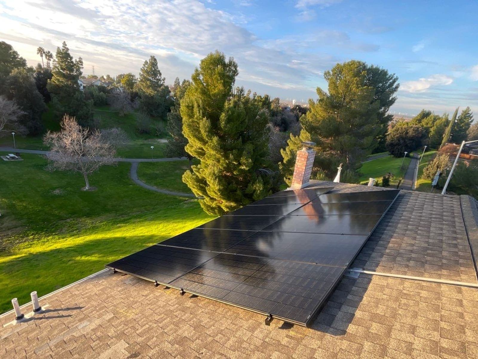 Solar array on a residential roof overlooking a green open-space park