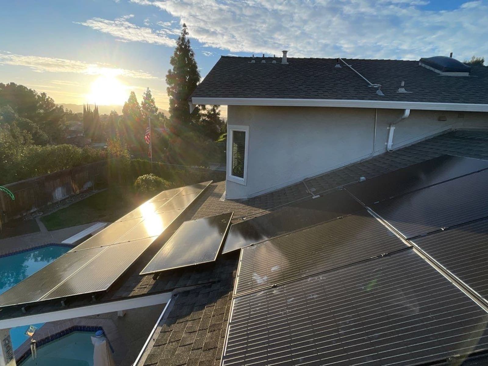 Rooftop solar array on a two-storey home at sunset, overlooking a backyard pool